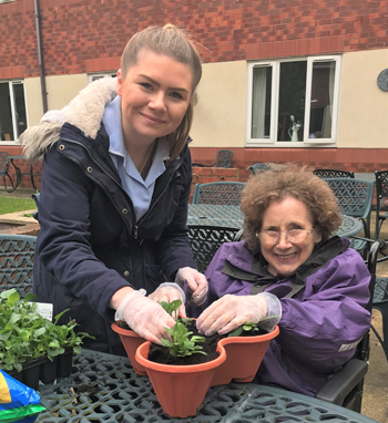 Carer Hope Povey and resident Sylvia Smith aiming to fill The Beeches Care Home garden with colour by planting flowers.